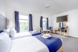 a hotel room with two beds and a flat screen tv at Abbey Lawn Hotel in Torquay