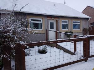 a house with a fence in the snow at Rosemarie's B&B in Lochcarron