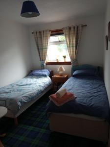 a bedroom with two beds and a window at Rosemarie's B&B in Lochcarron