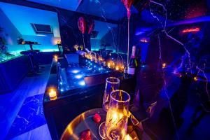 a room with purple lights and a table with glasses at Love Room Serenity Suite in Montbéliard