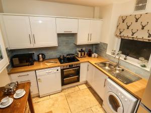 a kitchen with white cabinets and a sink at Waterhead Cottage in Ambleside +20 photos
