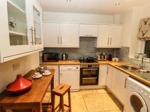 a kitchen with white cabinets and a wooden table at Waterhead Cottage in Ambleside
