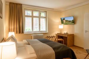 a bedroom with a bed and a desk and a window at Klosterhotel Lehnin in Lehnin