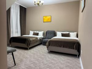 ein Hotelzimmer mit zwei Betten und einem Stuhl in der Unterkunft Vila Verde in Chişinău