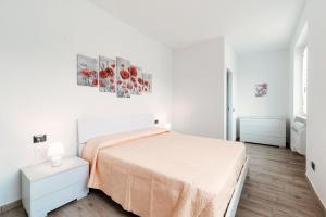 a white bedroom with a bed and a painting on the wall at Lake Como Retreat Menaggio in Menaggio