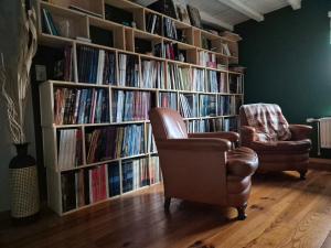 a library with two chairs and book shelves filled with books at Chambre de Arnaud à Gerpinnes in Gerpinnes