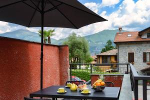 a table with a bowl of fruit and an umbrella at Lake Como Retreat Menaggio in Menaggio
