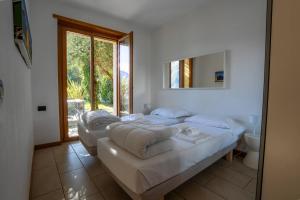 a white bedroom with two beds and a mirror at Residence degli Oleandri APP A1 in Argegno