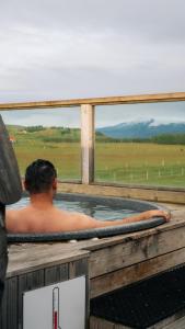 a man in a jacuzzi tub on a deck at Midgard Base Camp in Hvolsvöllur
