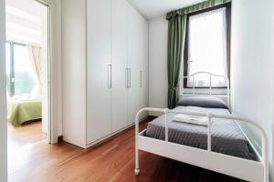 a white bedroom with a bed and a window at Villa Citriodora in Cernobbio