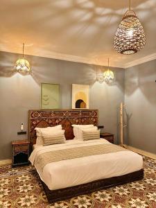 a bedroom with a large bed and two chandeliers at riad tighmart in Merzouga +17 photos
