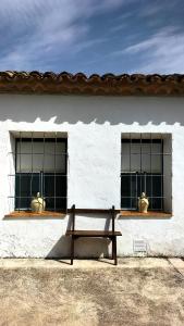 a bench in front of a white building with windows at Malpesa Rural in Poveda de la Obispalía