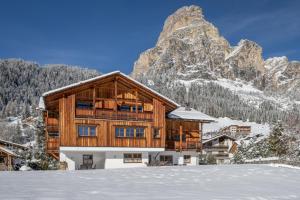 a house in the snow with a mountain at Chalet Ciasa Tino & Sara - BelaVal Apartments in Corvara in Badia