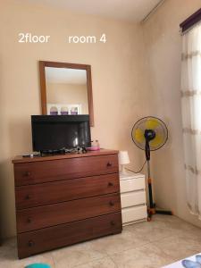 a bedroom with a dresser with a tv and a mirror at guesthouse emaly in Mindelo