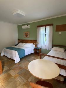 a hotel room with two beds and a table at Pousada Paisagem in Paraty +60 photos