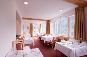 ein Restaurant mit weißen Tischen, Stühlen und Fenstern in der Unterkunft Hotel Alpenfriede in Jerzens