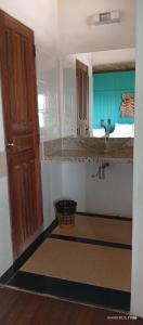 a bathroom with a sink and a door and a basket at Pousada Bosque dos Aruãs in Salvaterra