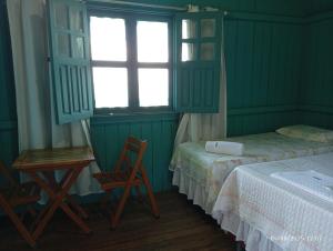 a bedroom with two beds and a table and a chair at Pousada Bosque dos Aruãs in Salvaterra