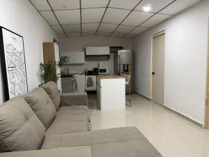 a living room with a couch and a kitchen at Ciudad Merliot, casa Don Pablo in Hacienda Plan de La Laguna