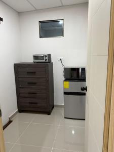 a small kitchen with a microwave and a refrigerator at Ciudad Merliot, casa Don Pablo in Hacienda Plan de La Laguna +10 photos
