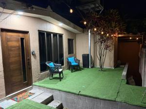 a house with two chairs and a green floor at Ciudad Merliot, casa Don Pablo in Hacienda Plan de La Laguna