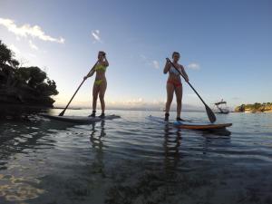 two women are standing on paddle boards in the water at MolaMola House in Nusa Lembongan