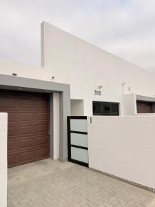 a white building with a garage and a brown door at 268 Self-catering Apartments in Swakopmund