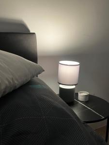 a bed with a table with a lamp on it at Apartament Rynek Strzelin in Strzelin