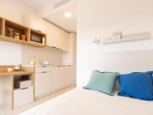 a kitchen with white cabinets and blue pillows on a bed at Canvas Sabadell Llac in Sabadell +19 photos