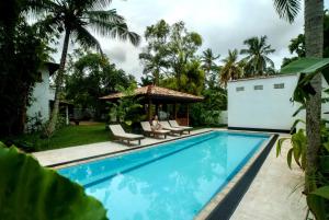 a woman sitting on a chair next to a swimming pool at Tara Luxury House in Habaraduwa Central
