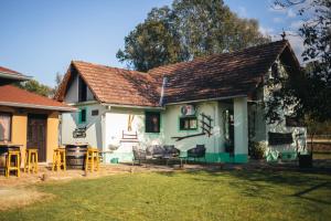 a green and white house with chairs and a grill at Kuća za odmor San in Lonja