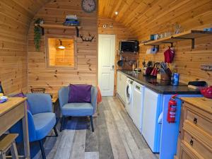 a kitchen in a log cabin with a counter and chairs at Rowan Gorgeous Glamping Hideaway in Durnamuck