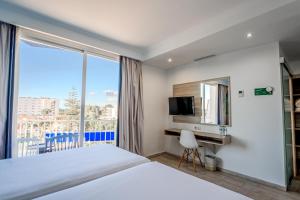 a hotel room with a bed and a desk and a window at NURA Boreal in Playa de Palma