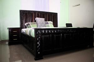 a bedroom with a black bed with a wooden frame at Mamboleo princely Homes in Kisumu +2 photos