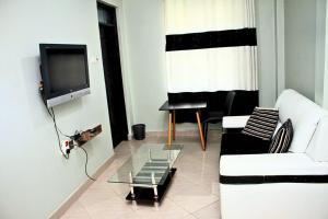 a living room with a white couch and a tv at Mamboleo princely Homes in Kisumu