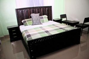 a bed with a checkered blanket and two chairs at Mamboleo princely Homes in Kisumu