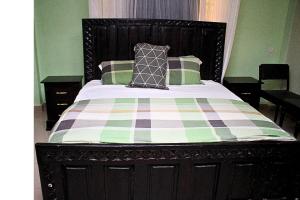 a bed with a checkered blanket and pillows on it at Mamboleo princely Homes in Kisumu
