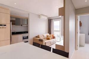 a room with a bed and a couch and a kitchen at Curta Praia do Quilombo - Palladium in Penha