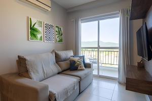 a living room with a couch and a large window at Curta Praia do Quilombo - Palladium in Penha