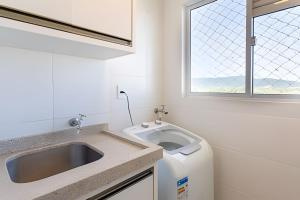 a white kitchen with a sink and a window at Curta Praia do Quilombo - Palladium in Penha +258 photos