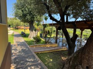 a garden with a wooden pergola and tables and trees at Villaggio Turistico La Fenosa in Marina di Camerota
