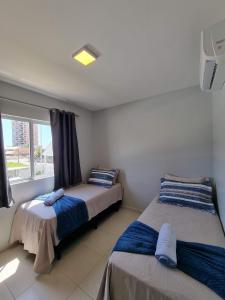 two beds in a room with a window at Curta Praia do Quilombo - Palladium in Penha