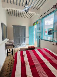 a bedroom with a red and white bed and a piano at Riad darkoum in Essaouira