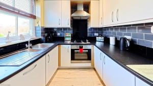 a kitchen with white cabinets and black counter tops at Greenwich Cottage - Part of the The Bay Filey Holiday Village with pool, gym and direct beach access, pub, restaurant, tennis and meadows walks in Reighton +46 photos