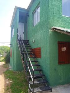 a green building with stairs leading up to a door at Los Cali 27 planta alta 1 in Balneario Buenos Aires