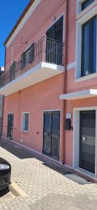 a pink building with black doors and a balcony at House Pale Rooms in Palau +20 photos