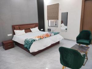 a bedroom with a bed and two green chairs at Kamadgiri Green Valley in Nawābganj