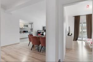 a white kitchen and dining room with a table and chairs at Apartament 2 dormitoare spatios, Aer conditionat, Flat Screen TV, Self Check-in in Ştefăneştii de Sus