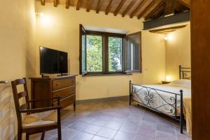 a bedroom with a bed and a tv and a chair at Villa Montarioso in Siena