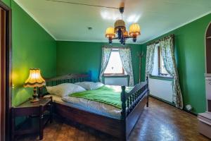 a bedroom with a bed with green walls and a chandelier at KRO906-Lidhult-Torseryd-4 in Lidhult